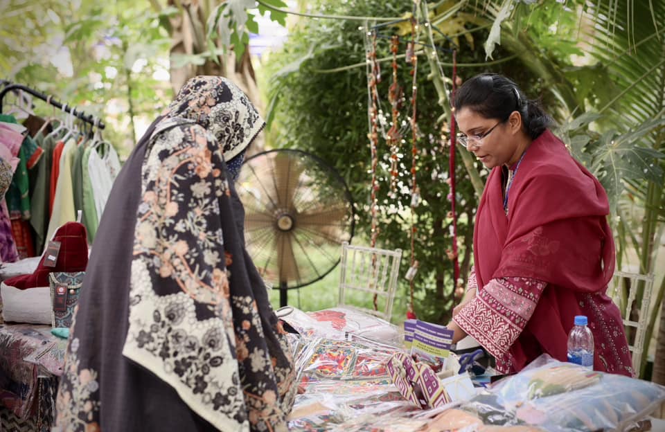Customer browsing textiles and products at a bazaar stall